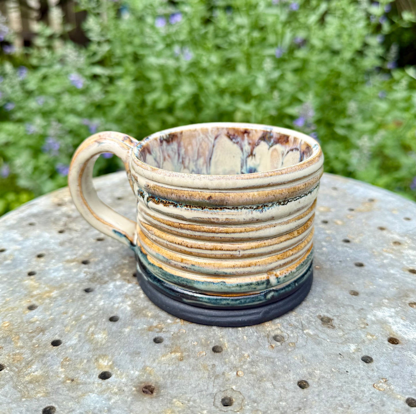 Side view of handmade stoneware mug showing mountain ridges