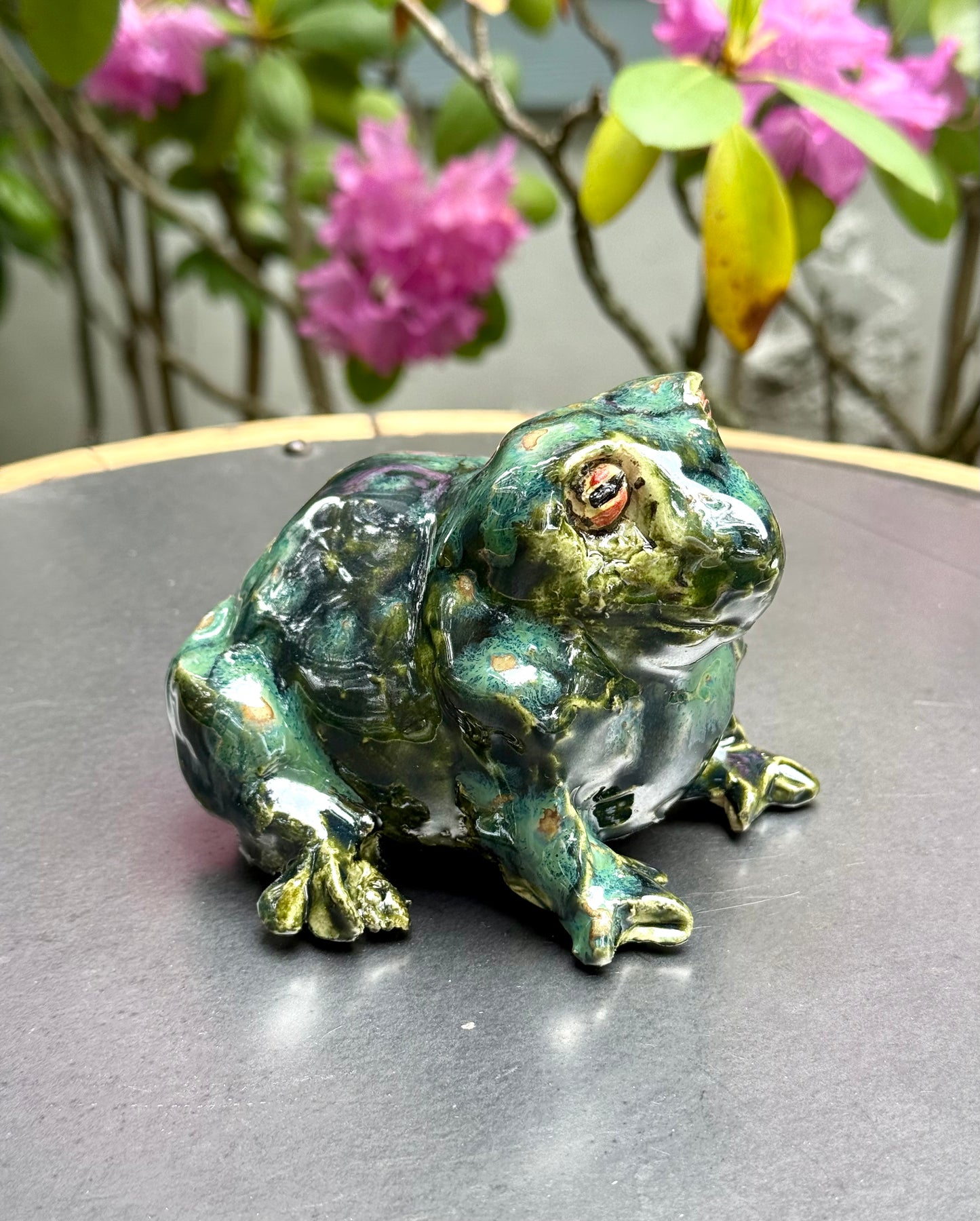Side view of ceramic frog garden ornament showing detailed texture