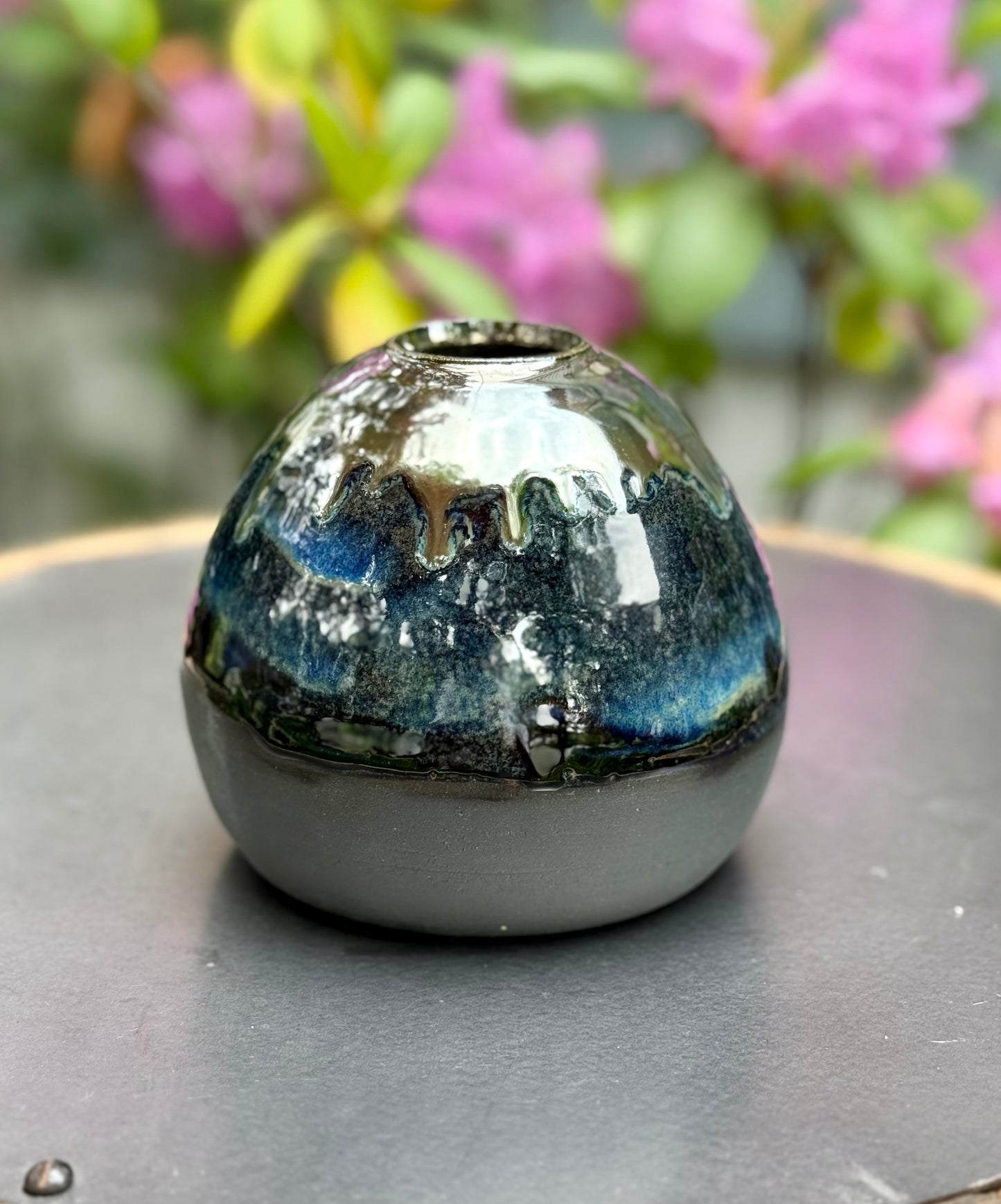 Handmade ceramic vase with iridescent blue-green glaze reflecting light