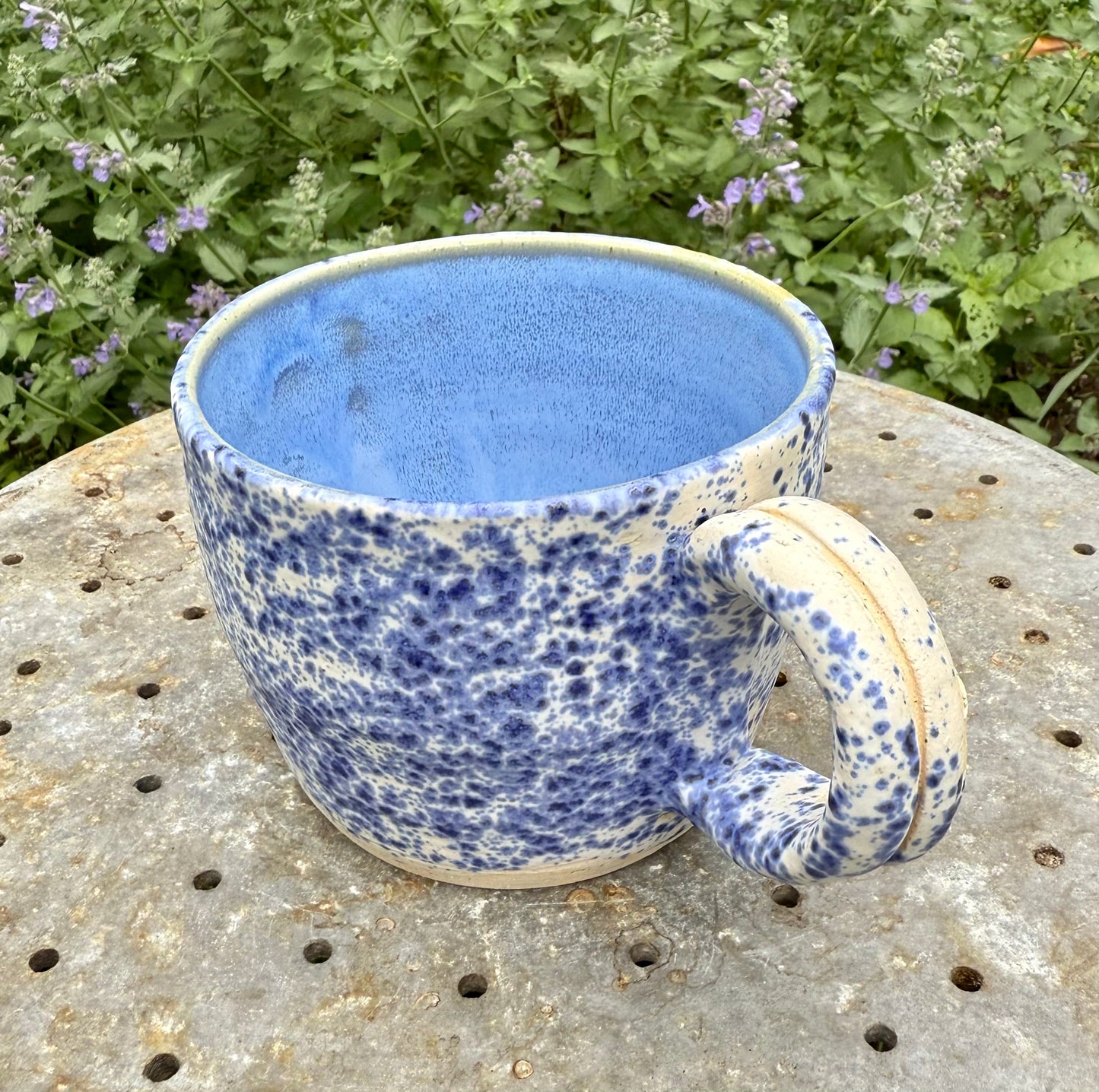 Close-up view of speckled blue glaze and interior solid pale blue glaze on handmade ceramic mug