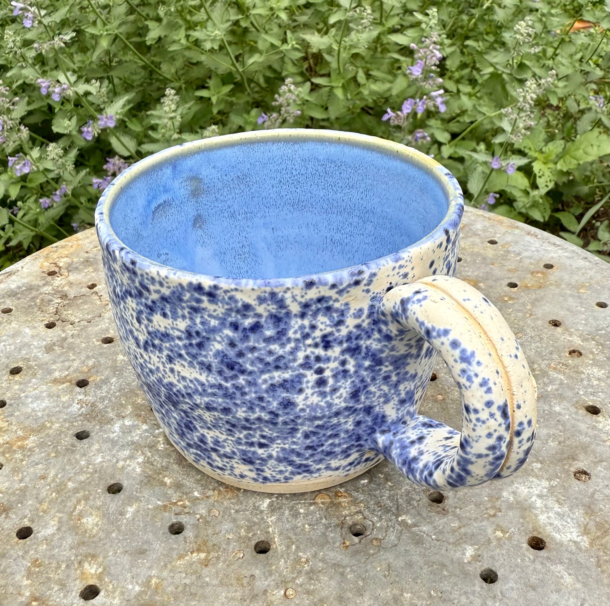 Close-up view of speckled blue glaze and interior solid pale blue glaze on handmade ceramic mug